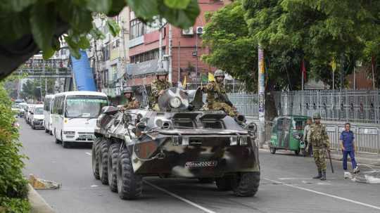 Vojaci vo vozidle ozbrojených síl hliadkujú v uliciach počas protestov v Dháke.