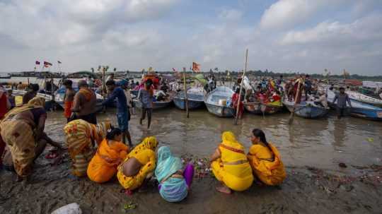 Ľudia sedia pri vode počas festivalu v Indii.