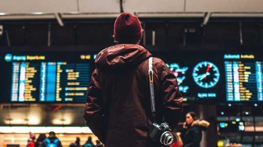 Muž na letisku pozerá na svetelnú tabuľu.
