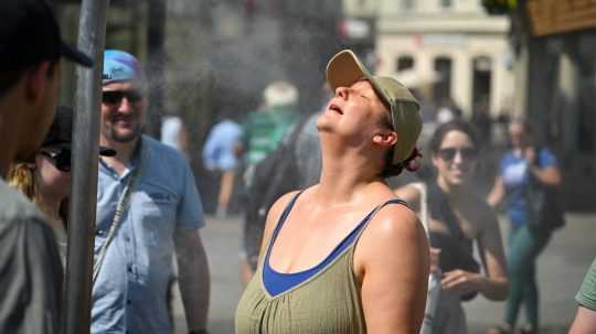 Žena sa osviežuje pod rozprašovačom počas horúceho dňa v Bratislave.