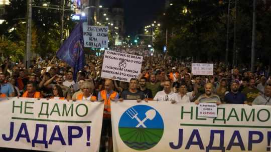 Ľudia držia transparenty a pochodujú počas protestu proti projektu na ťažbu lítia v Srbsku.