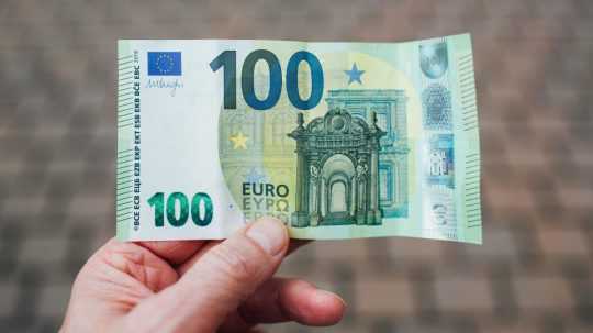 Osoba na sníme drží 100-eurovú bankovku.