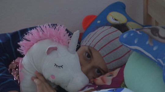 Na snímke dievčatko leží v posteli a objíma plyšovú hračku.