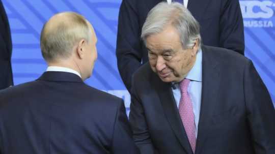 Ruský prezident Vladimir Putin (vľavo) a generálny tajomník OSN António Guterres si podávajú ruky.