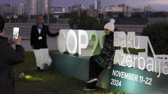 Ľudia pózujú pri logu v dejisku Klimatickej konferencie OSN COP 29 v Baku.